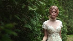 Bride Looks From The Tree. Lovely Blonde Between The Trees In The Forest.