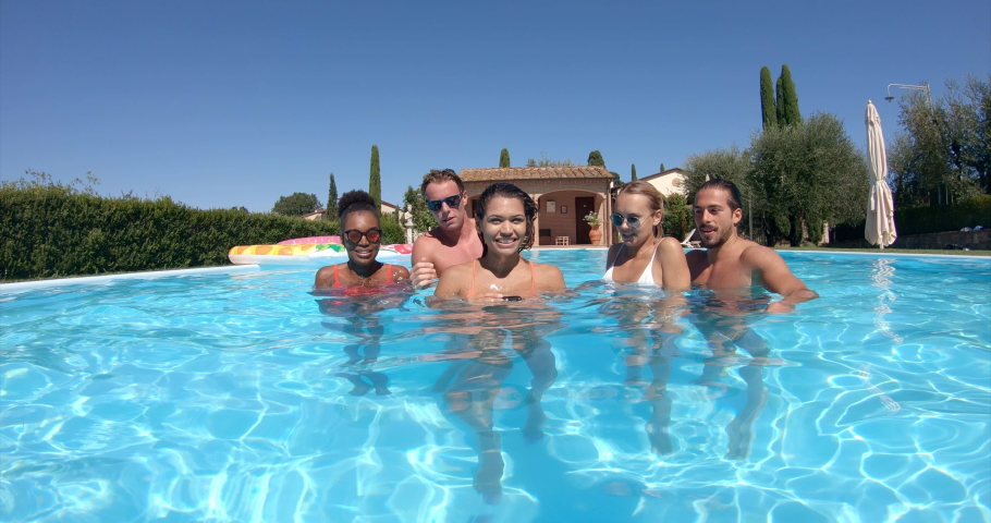 Underwater shot of young multi-ethnic friends in swimwear are having fun to enjoy their summer vacation and making selfie in swimming pool underwater in a sunny day. Royalty-Free Stock Footage #1037656004