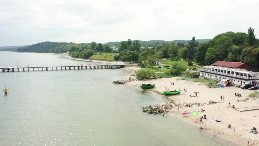 Aerial view of fishing boats elongated on the sandy shore in the Baltic Sea. ?ity of Gdynia, Poland. Two green ships stand on the beach on a sunny summer day.