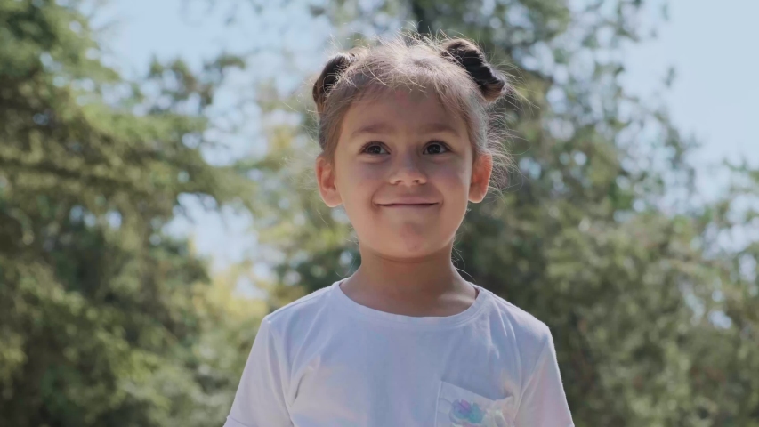 Happy cute little girl in white t-shirt portrait. Smiling preschooler. 4K video.