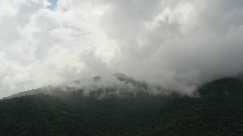 Aerial view of Mountains lush in rain clouds covering mountains, tropical rainforests during the rainy season.
