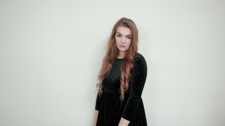 girl brown haired in black dress over isolated white background shows emotions