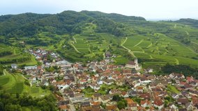 Aerial view of the village Kiechlinsbergen am Kaiserstuhl in Germany on a sunny day in summer. Pan to the left with wide view of the village. 