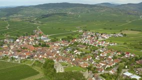 Aerial view of the village Burkheim am Kaiserstuhl in Germany on a sunny day in summer. Wide view  wth pan to the right from the village to fields.