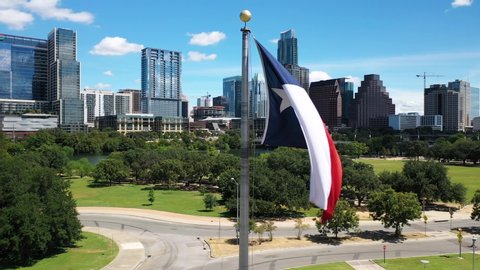 4K Aerial Texas Flag Blows in Wind Austin Skyline Orbit