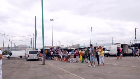 Malaga/Spain - 09-08-2019 : fixed shot of a parking where a flea market takes place. Many stalls, trucks, people and tourists enjoying the place.