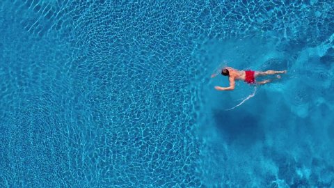 Aerial view of man in red shorts swims in the pool