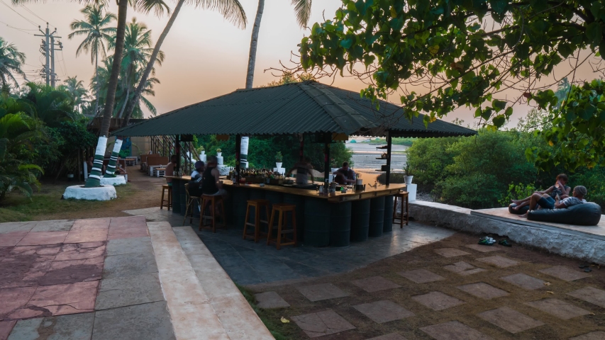 Beach-side restaurant cafe bar lit by flaming torches, at sunset in tropical Goa. Idyllic romantic summer night dining under a purple sky. | Shutterstock HD Video #1037678072