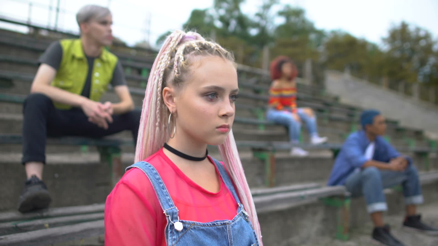 Serious female millennial looking camera sitting college stadium, new generation