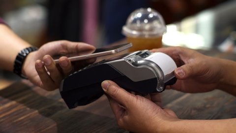 4K Locked shot with barista served ice beverage and send the credit transaction to customer making contactless payment for using paying by smartphone in coffee shop, NFC technology