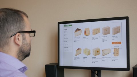 A man orders food home in an online store. The businessman selects the cheese in the grocery online store. 4K UHD. New York, July - 2018