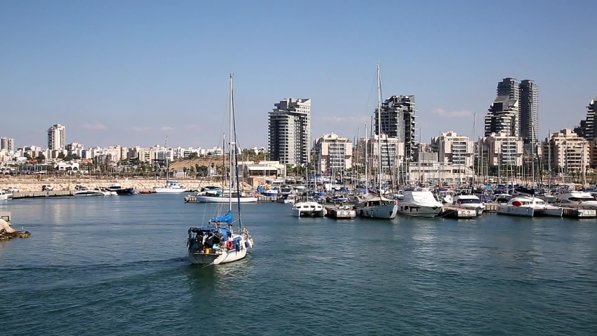 Yacht sailing to the pier of the yacht club in Ashdod against the background of the urban landscape. Israel