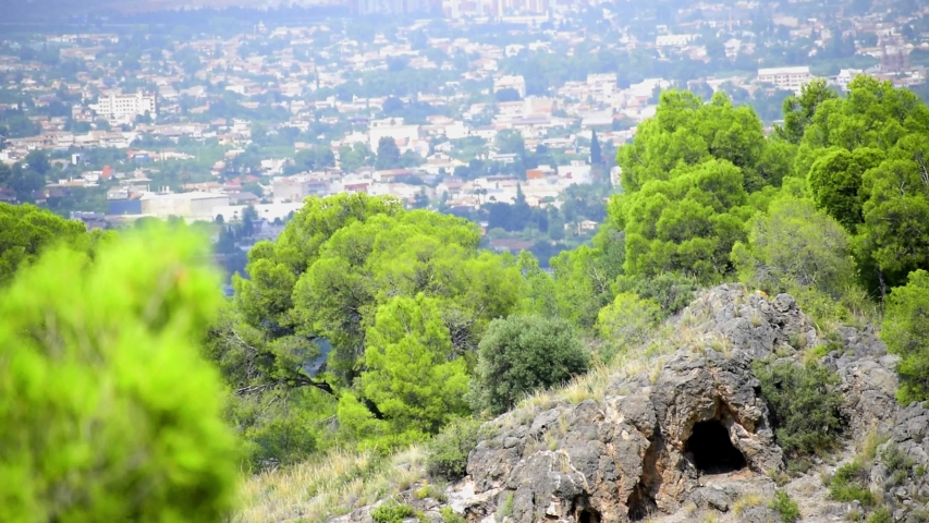 A hidden cavern at the top of the mountain against cityscape