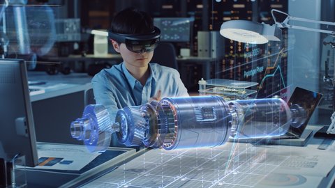 Industrial Factory Chief Engineer Wearing AR Headset Designs a Prototype of an Electric Motor on the Holographic Smart Blueprint. Futuristic Virtual Design of Mixed Technology Application.