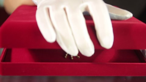 Hand in white glove opens red velvet jewelry box with silver pendant with magenta diamond.Jewellery.Jewelry store clerk