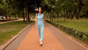 young caucasian woman walking on the street in city park brunette girl strolls outdoors summer nature background