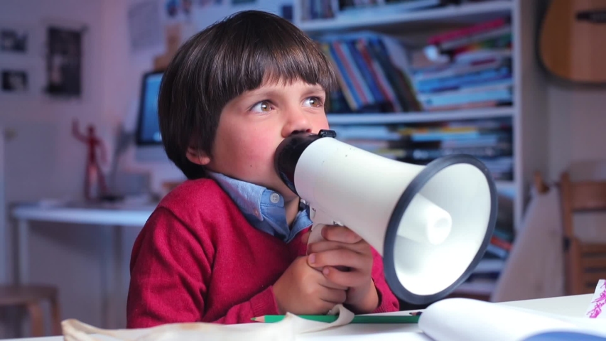 a lonely boy sits at a table in school, shouts loudly into a megaphone, protests Royalty-Free Stock Footage #1037719652