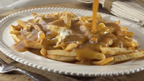 A serving of delicious poutine with french fries, melted cheese and gravy.