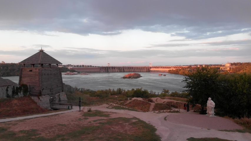 Panoramic view on the Dnieper Hydroelectric Station as seen from the Zaporizhian Sich (Khortytsia island). Closer aerial view at the dam during a sunset in 4K