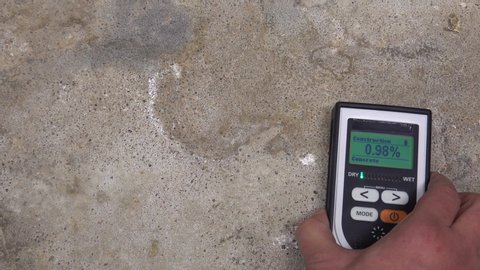 Man using moisture meter for house inspection and measuring moisture in basement. Concrete floor is wet. Video for home renovation and house industry.