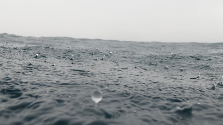 Slow motion of rain dropping into the endless ocean. Monsoon season in the Philippines brings bad weather that results to heavy rains and wild seas. Royalty-Free Stock Footage #1037738105