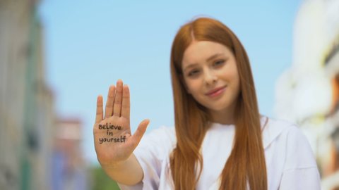 Young female showing palm with believe in yourself phrase, self-confidence