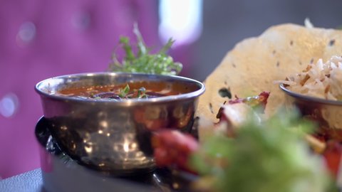 North indian rich cuisine meal items served in a steel platter, closeup panning shot