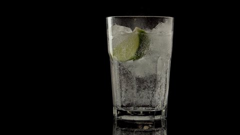
glass with tonic and lime on a black background