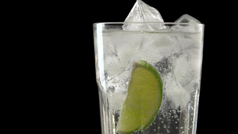 
glass with tonic and lime on a black background