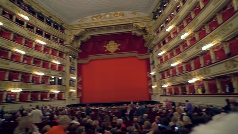 Milan Italy September 24, 2019: Alla Scala Theater. A view inside the building of a large red velvet room and an empty scene behind the curtain. The famous opera house. Orchestra of lasic music