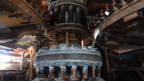 Zaandam Zaanse Schans near Amsterdan inside typical dutch windmill large wooden wheels grinding peanuts automated process by wind on blades outside mill old industrial process. Slow motion. Close up