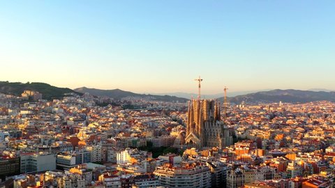 Barcelona / Spain - 08 23 2019: La Sagrada familia cathedral, Aerial, tracking, drone shot, around the church, under construction, over the cityscape of Barcelona city, at sunset, on a sunny, summer e