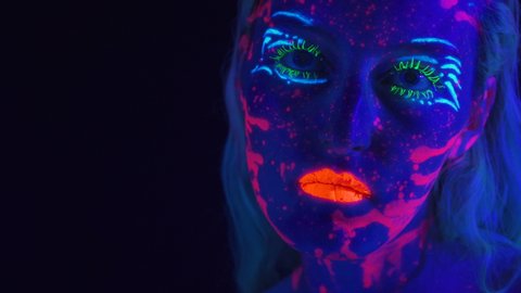 Video of young woman with bright bodyart in ultraviolet light
