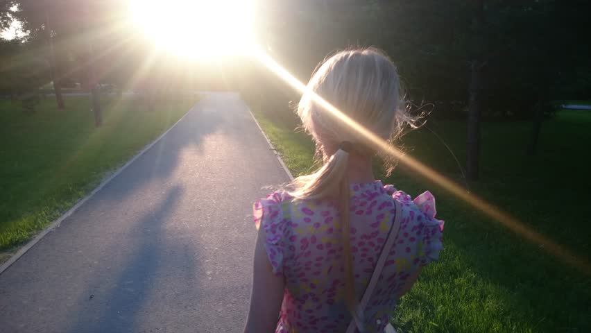 Beautiful girl in a sundress walking in park, evening light.