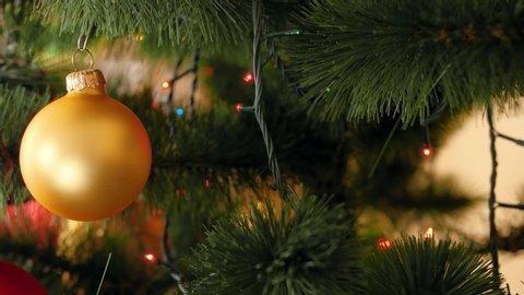 4k panning footage from slider of beautiful colorful balls and glowing Christmas lights on fire tree branches. Perfect shot for your winter holidays and celebrations