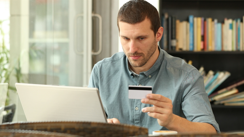 Worried man buying online with credit card and laptop in a coffee shop Royalty-Free Stock Footage #1037777957