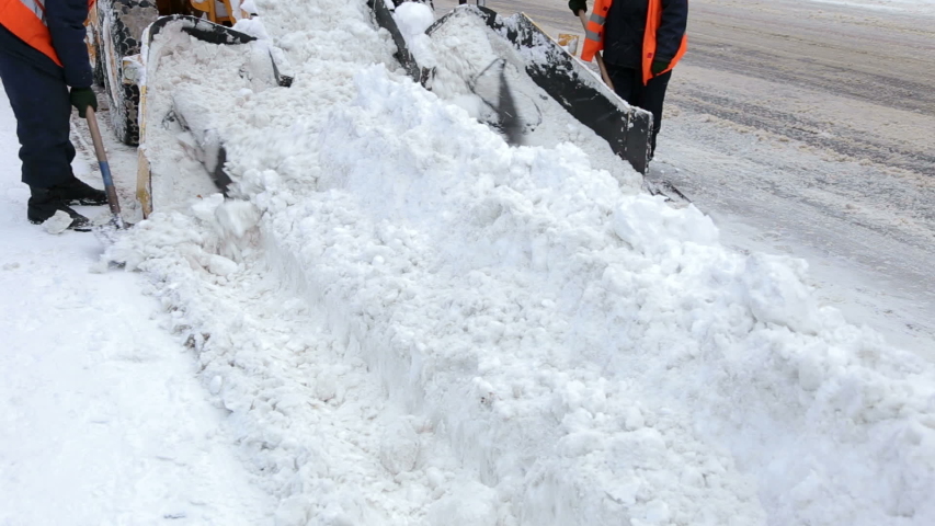 Specialized snow plow works on city streets after a heavy snowstorm, large mechanical shovels scoop up snow and load it into the truck.