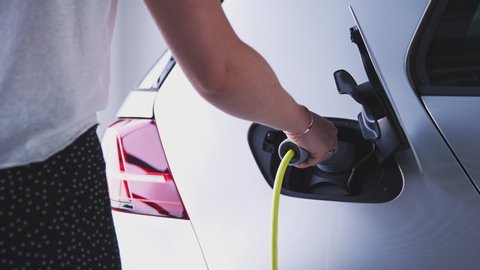 Close Up Of Hand Attaching Power Cable To Environmentally Friendly Zero Emission Electric Car
