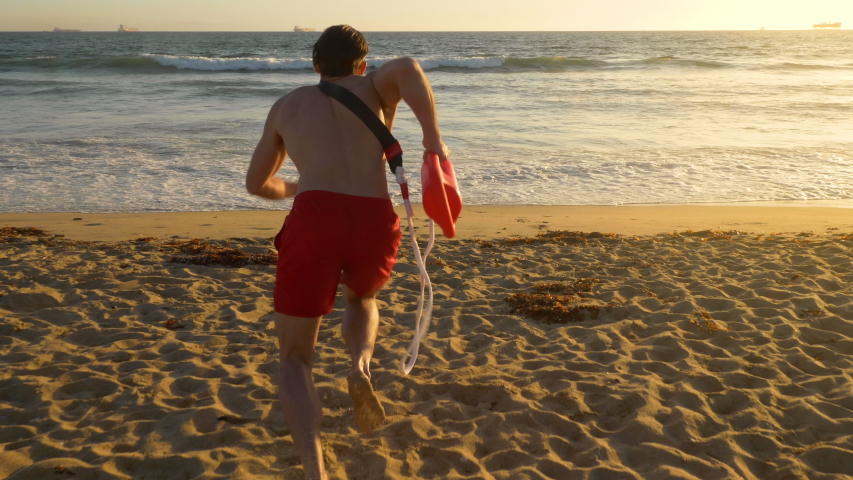 Male lifeguard running along the beach Royalty-Free Stock Footage #1037788235