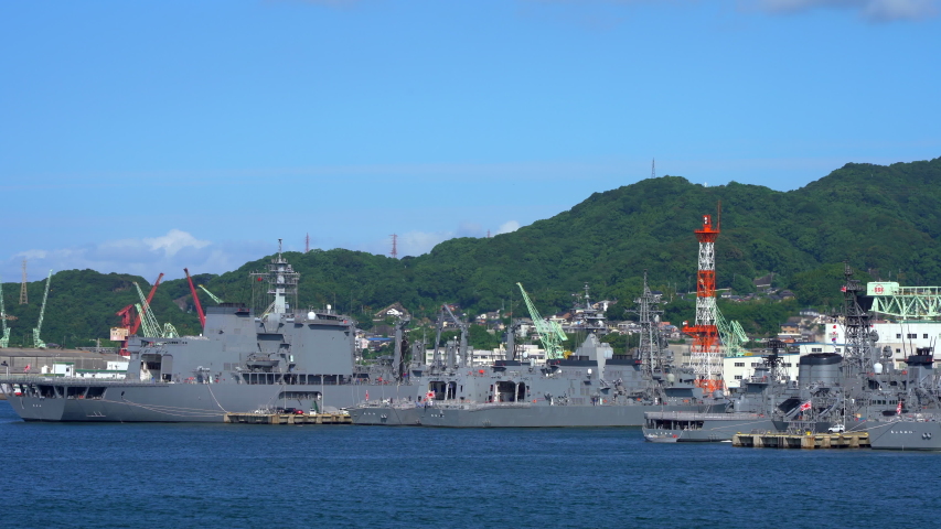 
military port on the japanese island. large gray warships moored in the port on an end day. drone view