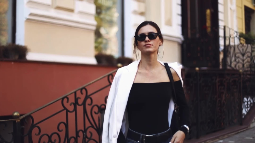 Brunette young sexy woman with low bun look at camera smile walking in the city. Streets portrait beautiful lady outdoor. Business lifestyle. Pretty woman. Fashion minimalist look.