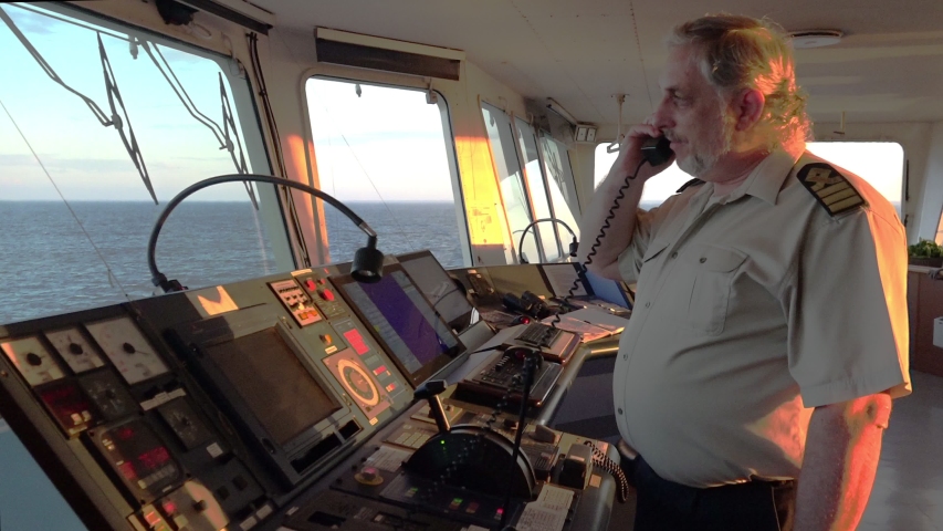 Senior ship master talks on telephone and looks at blue endless sea in vessel command post in summer evening Royalty-Free Stock Footage #1037791190
