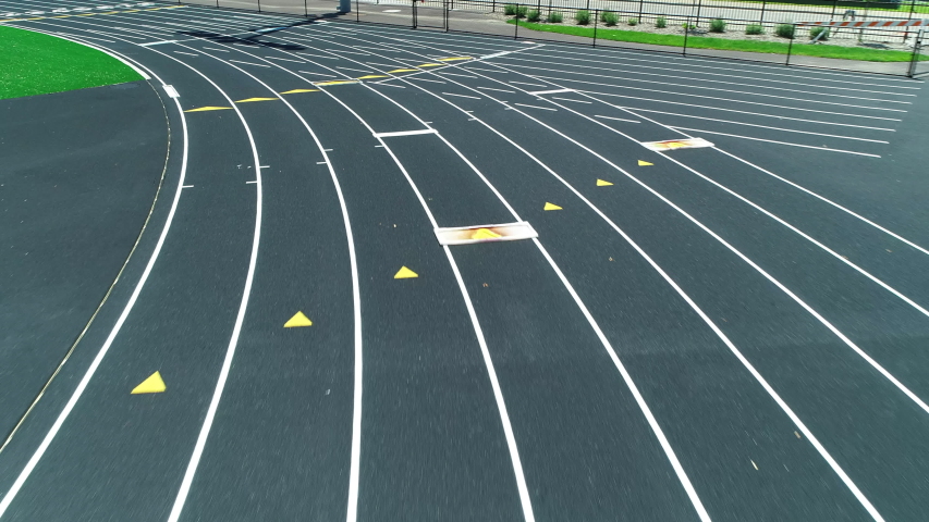 Drone aerial shot racing along athletic stadium running track. Themes of competition, sports, champion, hard work. Prores file, shot in 4K. Royalty-Free Stock Footage #1037801183