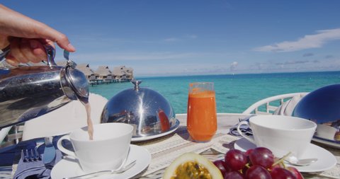Vacation breakfast table at luxury restaurant or hotel room by the water in the tropics. Romantic honeymoon travel holiday.