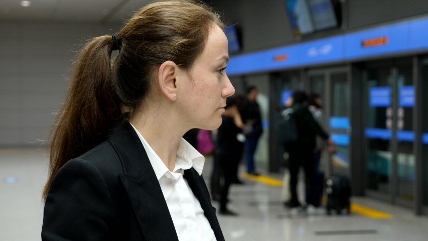 Portrait of passenger woman, airport train arrive and people go inside carriage, blurred background. Modern international airport sterile area, driverless train used to travel between terminals