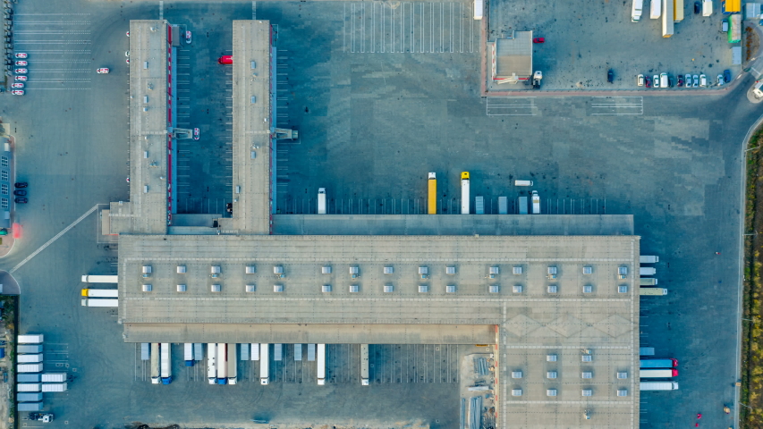 Aerial top view of the large logistics park with warehouse, loading hub with many semi-trailers trucks standing at the ramps for load/unload goods at night. Hyper lapse (hyperlapse - time lapse) Royalty-Free Stock Footage #1037818877