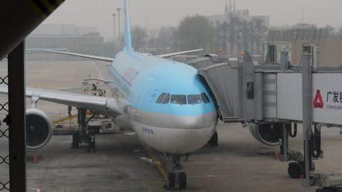 BEIJING - MARCH 27, 2018: Korean Air plane parked at gate of large international airport, view from terminal. Short clip of modern airliner standing at apron with boarding bridges connected