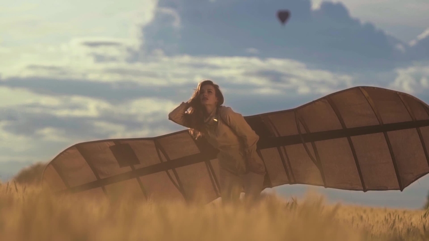 Young girl with wings dreaming to fly in summer field