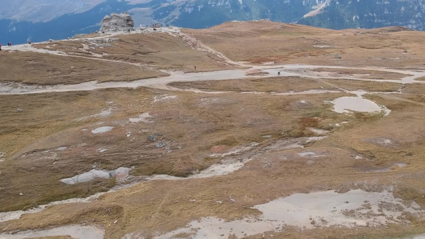 aerial shooting in the mountains. Tourists are photographed near a rock with a strange shape. Filming made in the Bucegi Mountains in Romania.