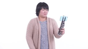 Happy overweight Asian woman vlogging with phone ready for winter